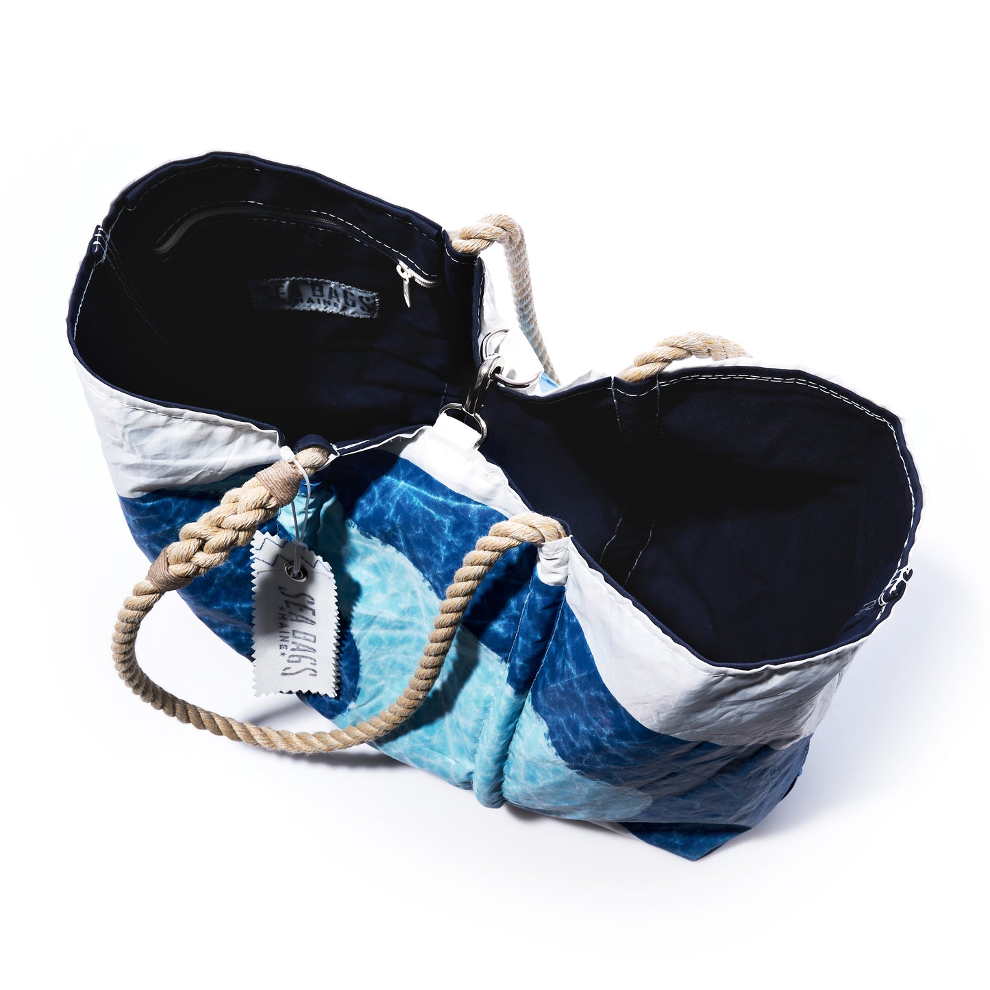 Sea Bags Auction Sun-Washed Sailboat Large Tote, featuring blue and white sailcloth with rope handles, is shown open to reveal two black fabric-lined compartments against a white background.