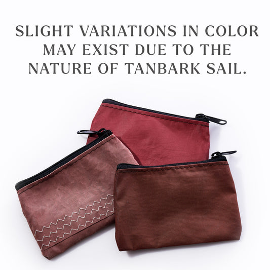 Three Sea Bags Tanbark Everyday Carry Mini Pouches are displayed in an array of reddish-brown hues, each one crafted from recycled tanbark sail for a distinctive link to maritime heritage. The text above notes that slight color variations may occur due to the nature of the repurposed material. by Sea Bags