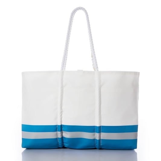 The Detroit Lions Tailgate Tote by Sea Bags is a white tote bag crafted from recycled sail cloth, featuring blue and gray horizontal stripes at the bottom and two long white rope handles. Photographed on a white background, this stylish and eco-friendly bag is perfect for showing your Lions Pride at your next football tailgate. by Sea Bags