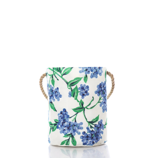 The Blueberry Print Bucket Bag by Sea Bags features a white ceramic design adorned with a blue and green floral pattern inspired by Maine blueberries, complete with rope handles on each side. Stylishly set against a white background, this versatile organizer adds charm to any room. by Sea Bags