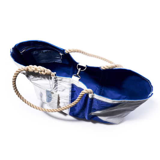 Sea Bags Alpha Signal Flag Large Tote features a blue and silver design crafted from recycled sail cloth, rope handles, an open top revealing a blue interior, metal clasp closure, and an attached tag inspired by vintage signal flags. by Sea Bags