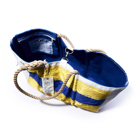 Introducing the Delta Signal Flag Large Tote by Sea Bags—a spacious carryall crafted from colorful, recycled sail cloth with sturdy rope handles, a bright blue interior, and an interior label. Its vibrant patchwork panels evoke the classic look of vintage signal flags found along coastal shores. by Sea Bags