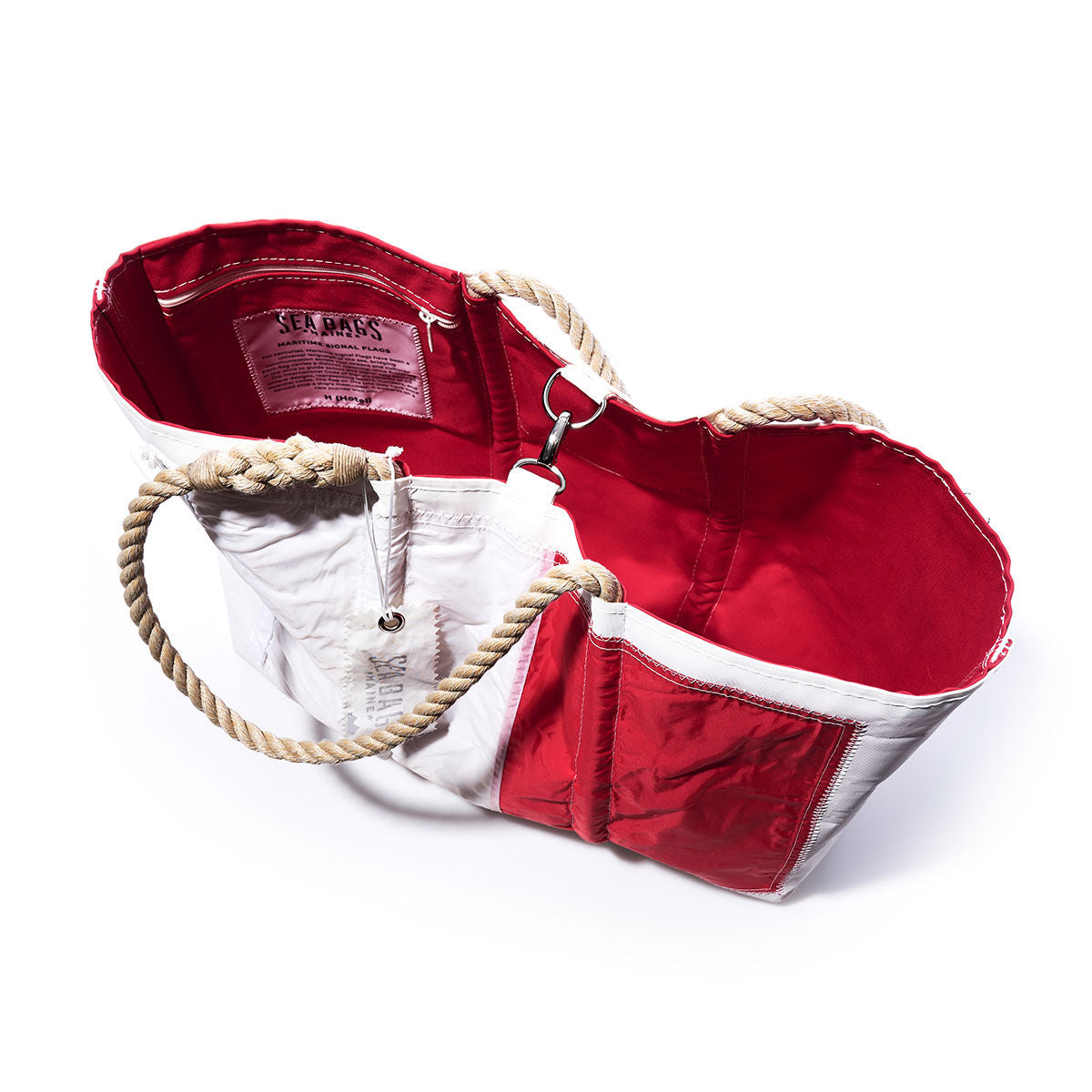 The Hotel Signal Flag Large Tote by Sea Bags is a red and white maritime bag crafted from recycled sail cloth, featuring sturdy rope handles, a vibrant red interior, an exterior pocket, and an interior label—shown photographed on a white background. by Sea Bags