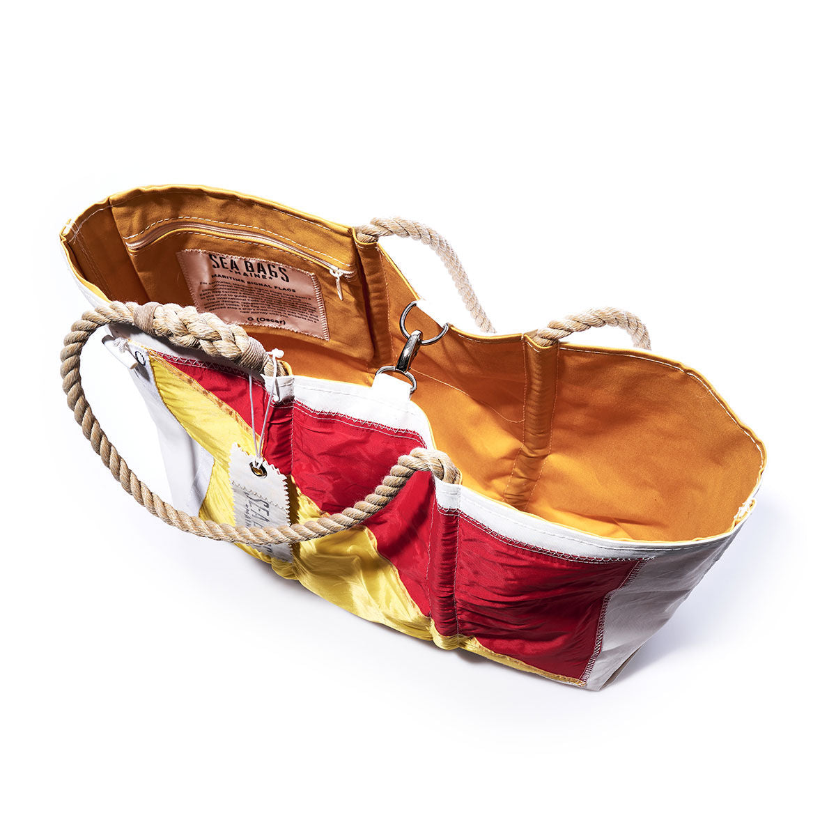 The Oscar Signal Flag Large Tote by Sea Bags is an open tote bag made from recycled sail cloth with sturdy rope handles. It showcases a patchwork exterior in red, yellow, and white panels inspired by vintage signal flags and features a vibrant yellow-orange inner lining. Inside, there is a small zip pocket and a visible label. by Sea Bags