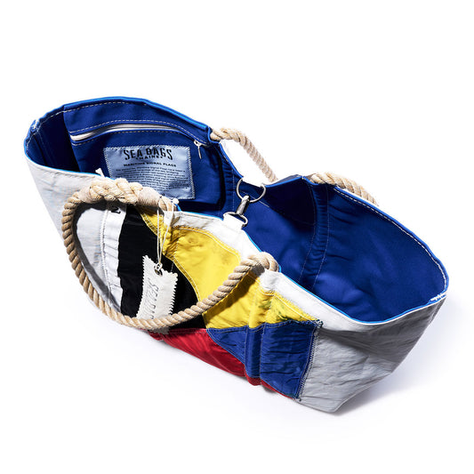 A Zulu Signal Flag Large Tote by Sea Bags, crafted from recycled sail cloth with rope handles, featuring a vintage signal flags design and an internal label, isolated on a white background. by Sea Bags