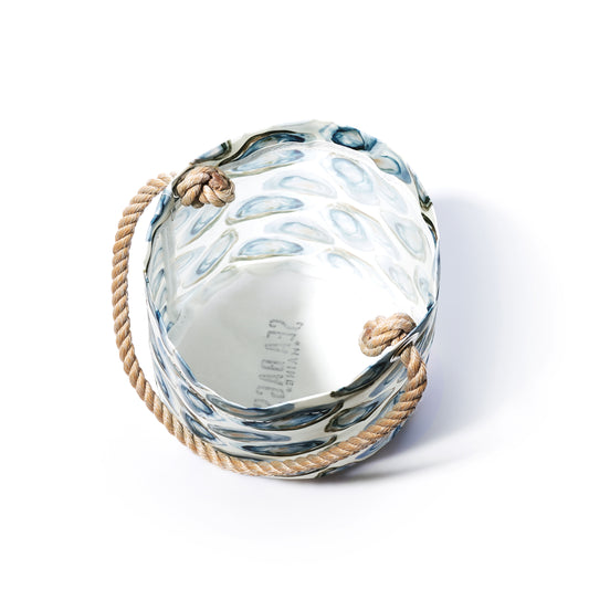 Sea Bags Watercolor Oyster Bucket—crafted from clear glass with a textured blue pattern and thick rope handles, echoing a coastal bucket bag—shown against a white background. by Sea Bags
