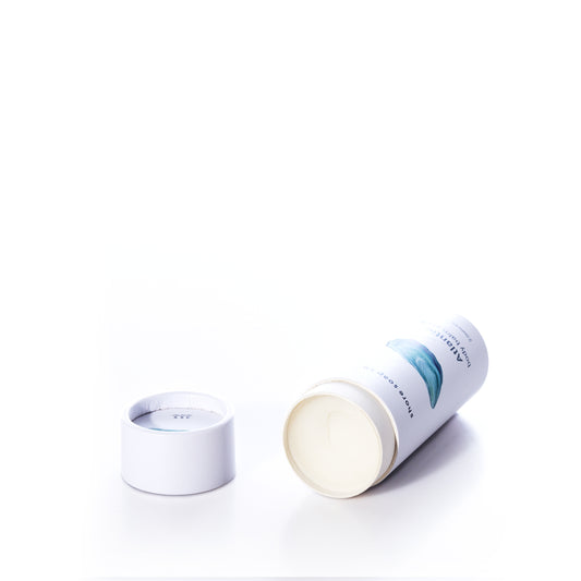 A white cylindrical container of true’s Atlantic Eco-Friendly Body Balm Stick lies on its side with the lid removed, revealing a concentrated moisturizer inside—perfect for hydrating dry skin—all against a white background.