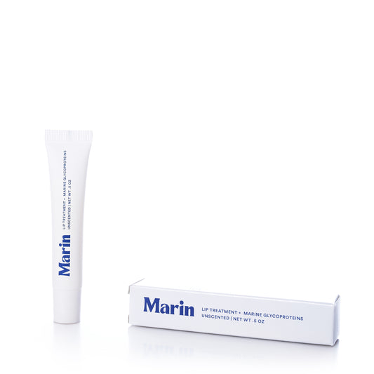 A white tube labeled Marin Skincare stands upright next to its matching box, both marked as Marin Lip Treatment - Unscented. This hydrating formula features marine glycoproteins and comes in a net weight of 0.5 oz.