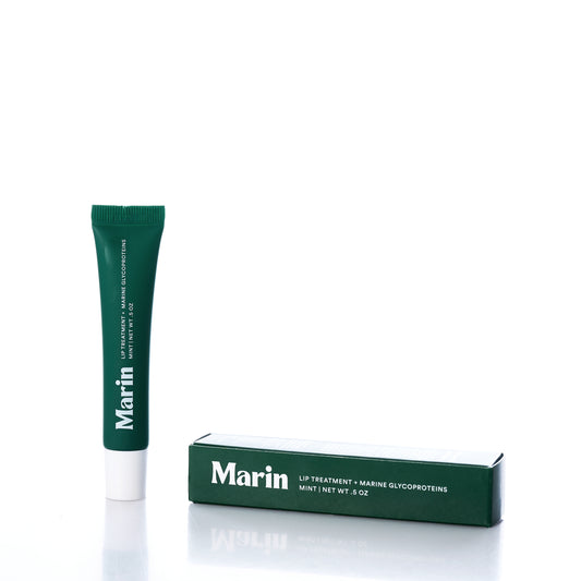 A green tube of Marin Skincare’s Marin Lip Treatment - Mint and its matching box are displayed upright on a white background. This hydrating lip treatment, formulated with Marine Glycoproteins, provides refreshing care for your lips. by Sea Bags