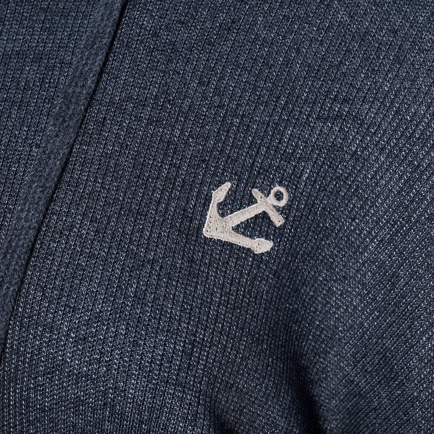 Close-up of the Soft As A Grape Ribbed Hoodie Pullover - Navy Anchor, showcasing its navy blue ribbed fabric and a small white embroidered anchor, perfect for bringing a subtle coastal style to your look. by Sea Bags