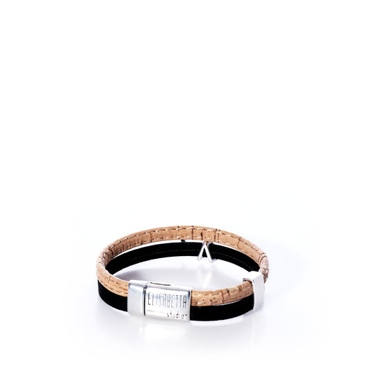 The Classic Cork Bracelet - Shark on Black by Elisabetta Studio features brown and black Portuguese cork with an antique silver shark magnetic clasp engraved with the brand name, shown against a white background. by Sea Bags