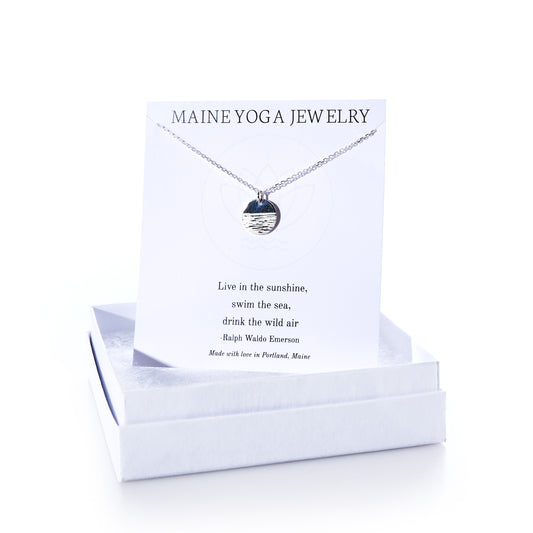 Horizon Silver pendant necklace by Maine Yoga Jewelry, featuring a round silver pendant displayed on a card with a Ralph Waldo Emerson quote, elegantly presented in a white jewelry box—an exquisite addition to any jewelry collection. by Sea Bags