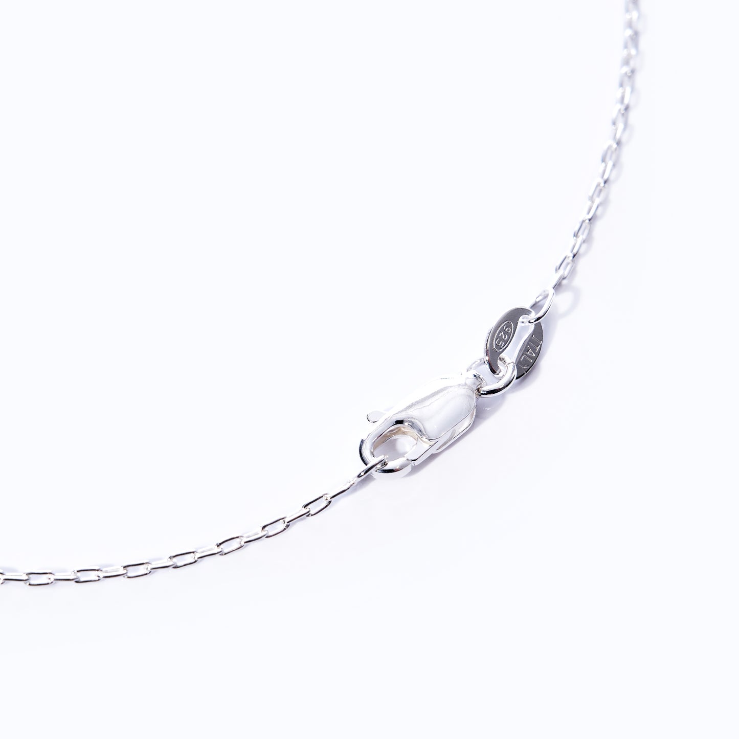 Close-up of the Maine Yoga Jewelry Pendant Necklace - Silver Compass Rose, featuring a silver chain with a lobster clasp and a small oval tag, set against a plain white background to highlight the classic elegance of this nautical-inspired piece. by Sea Bags