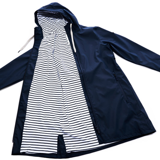 The Harborside Waterproof Raincoat - Navy by Batela USA Inc is shown open, displaying a white lining with black horizontal stripes. This unisex raincoat offers a waterproof shell for dependable protection during rainy days. by Sea Bags