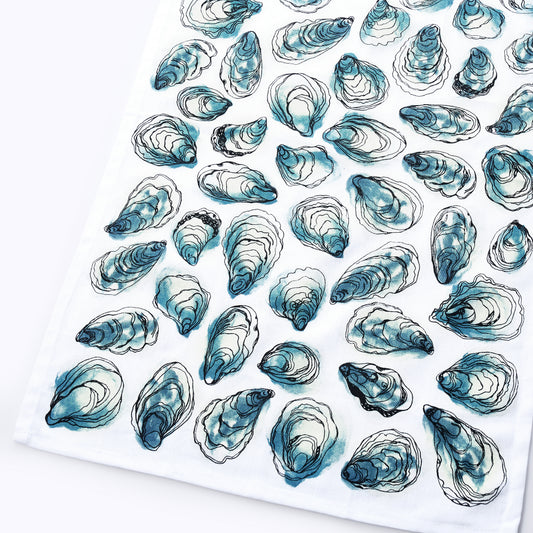 The Oysters Print Tea Towel by true is made from 100 white cotton and showcases a repeated pattern of blue and black oyster shell illustrations—perfect for adding a touch of coastal charm to your kitchen.