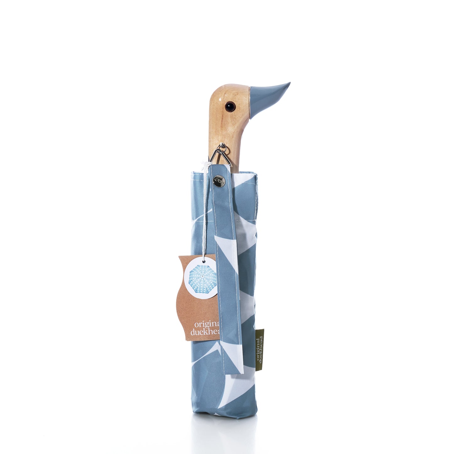 A folded Original Duck Head Umbrella - Denim Moon Print by ODH Limited, featuring a wooden handle shaped like a duck’s head and stored in a blue and white patterned cover with a tag attached. This wind-resistant umbrella combines charming design with practical durability.