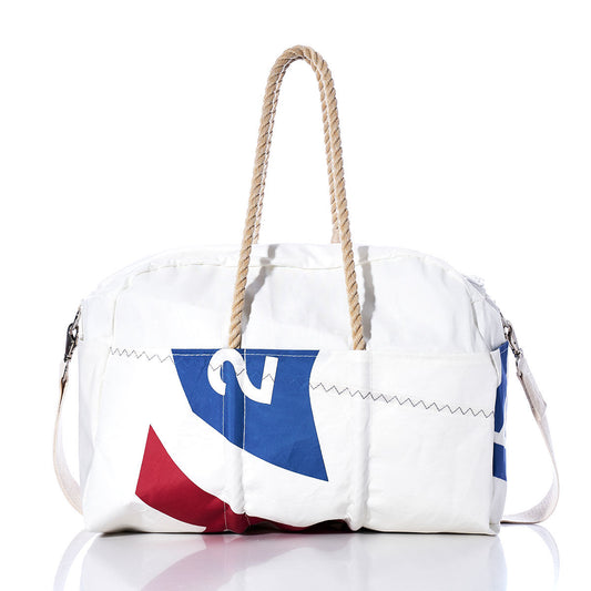 The Sea Bags Vintage Harbor 20 Weekender, a white bag with rope handles and blue and red graphic elements inspired by vintage harbor motifs, is photographed on a white background. by Sea Bags