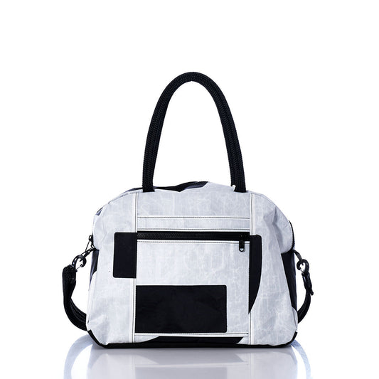 Sea Bags’ Vintage Black 2 Essential Weekender Travel Bag—a white and black travel bag with two handles, a front zippered pocket, black strap attachments, and a rectangular black patch design—features a built-in trolley sleeve for effortless transport and is displayed against a white background. by Sea Bags
