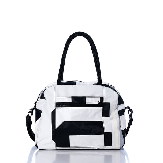 Sea Bags Vintage Black 5 Essential Weekender Travel Bag, featuring black geometric patterns, black handles, and a front zip pocket, is displayed on a white reflective surface—a stylish travel companion perfect for your next getaway. by Sea Bags