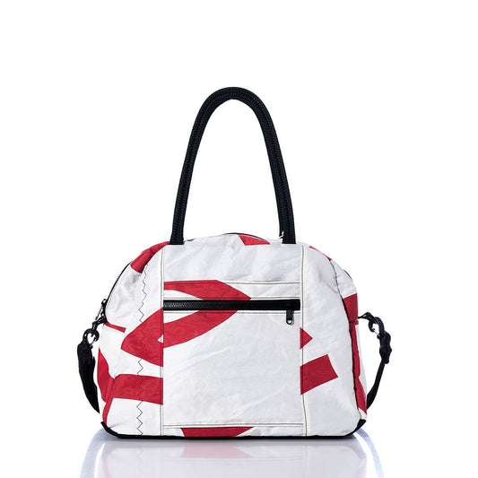 The Sea Bags Vintage Red and White Essential Weekender Travel Bag features red abstract patterns on a white background, black handles, a front zipper pocket, an adjustable shoulder strap, and a convenient trolley sleeve for easy travel. Designed as a compact carryon, the bag is displayed on a white reflective surface. by Sea Bags