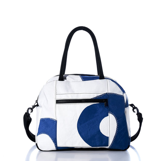 The Sea Bags Vintage Blue Numbers Essential Weekender Travel Bag, featuring a white and vintage blue design with black handles and a front zipper pocket, is displayed on a reflective surface against a white background—making it the perfect compact carryon or stylish weekender for your travels. by Sea Bags