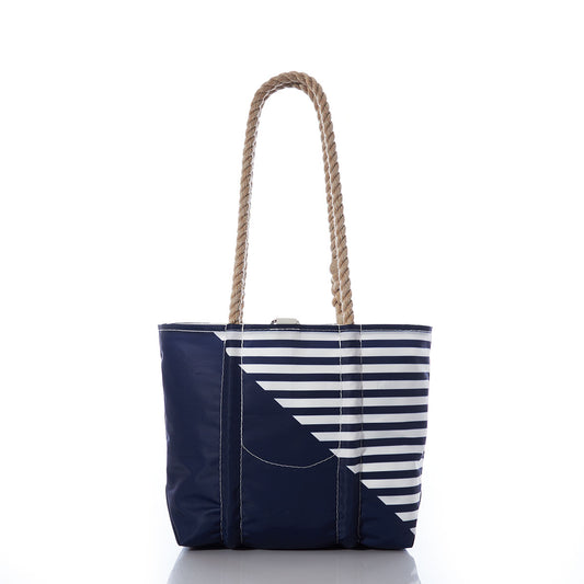 The Breton Stripe White Anchor Handbag by Sea Bags features navy blue and white diagonal stripes on one side, tan rope handles, and white stitching. Handcrafted in Maine from recycled sail cloth, this nautical tote is shown on a white background. by Sea Bags