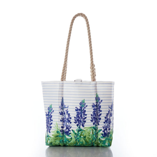 The Lupine Sailor Stripe Handbag by Sea Bags is crafted from recycled sail cloth and features rope handles, adorned with blue and green floral designs reminiscent of bluebonnets alongside light blue sailor stripes on a white background. by Sea Bags