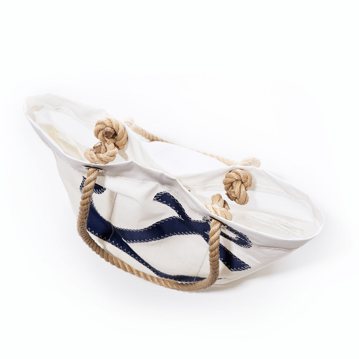 The Sea Bags Navy Anchor Essential Handbag features a white canvas design crafted from recycled sail cloth, accented with sturdy rope handles and a bold navy blue anchor motif. Shown on a plain white background, this eco-friendly tote is both stylish and functional—perfect for everyday use. by Sea Bags