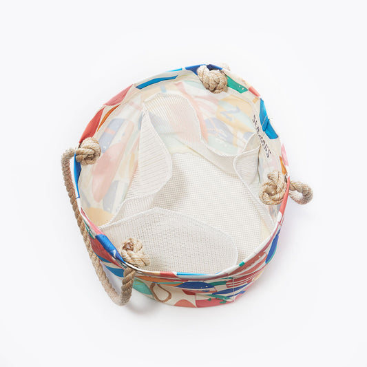 Sea Bags’ Downeast Buoys Beachcomber Bucket is a round, colorful tote bag featuring a mesh interior and sturdy rope handles, evoking the charm of traditional lobster fisherman gifts; shown from above against a plain white background. by Sea Bags