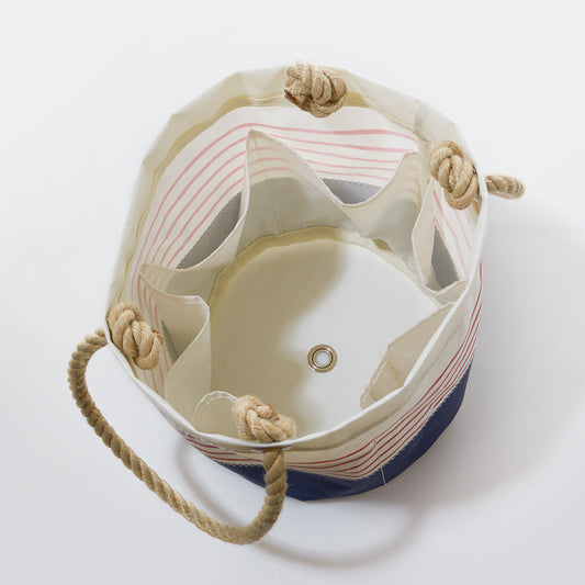 Sea Bags Red Mariner Stripe Beverage Bucket Bag is crafted from recycled sail cloth, features sturdy rope handles, interior pockets, and a metal grommet at the base—making it the perfect stylish collapsible cooler or beverage bucket when viewed from above. by Sea Bags