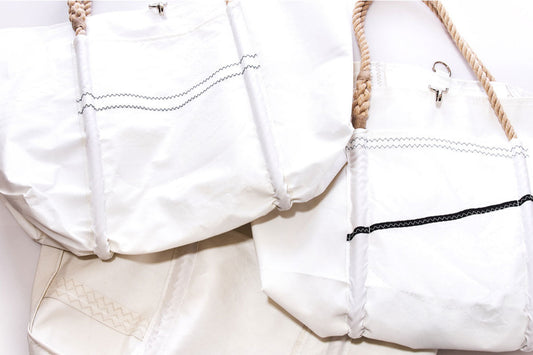 Three Sea Bags Wharf Tote bags—white with zigzag stitching and rope handles, inspired by classic sailcloth—are arranged close together on a light surface. by Sea Bags