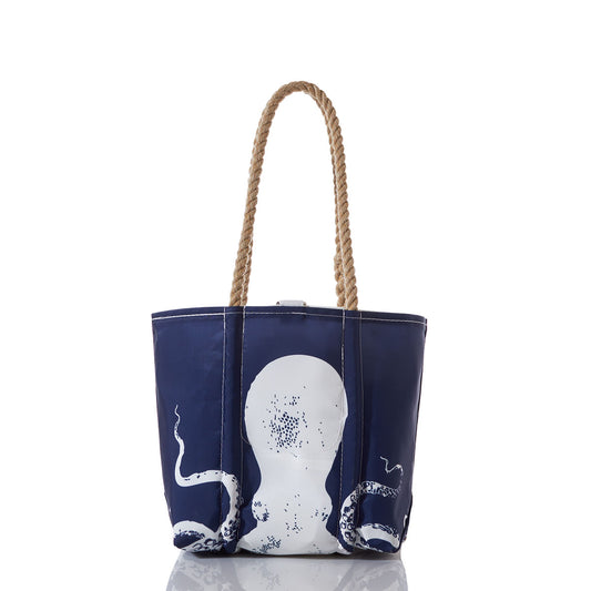 Sea Bags White on Navy Octopus Handbag features a white octopus graphic on a navy blue background, complemented by sturdy rope handles. Displayed on a white background with a subtle reflection beneath, this elegant handbag captures the spirit of oceanography and maritime adventures. by Sea Bags