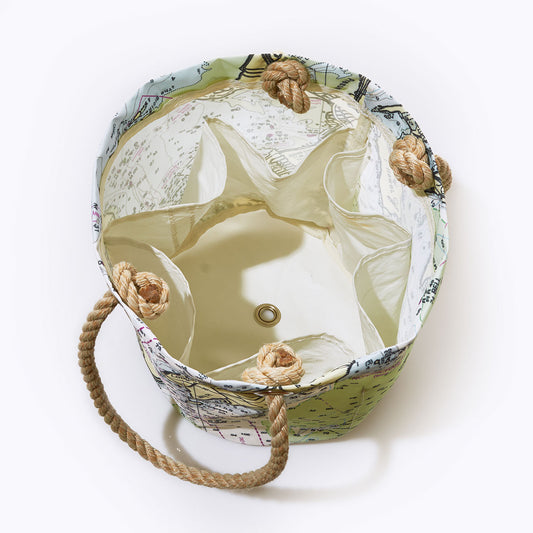 The Casco Bay Nautical Chart Beverage Bucket Bag by Sea Bags is crafted from recycled sail cloth and showcases a map print inspired by nautical charts. Rope handles threaded through metal grommets and multiple interior pockets are visible in this top-down view. by Sea Bags