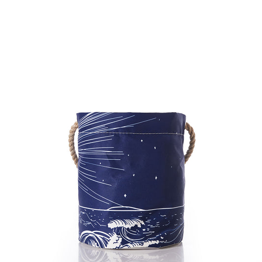 The Lighthouse Beacon Bucket Bag by Sea Bags is a navy blue fabric storage basket showcasing a white wave and star design inspired by Maine lighthouse motifs, and features two rope handles on the sides. by Sea Bags