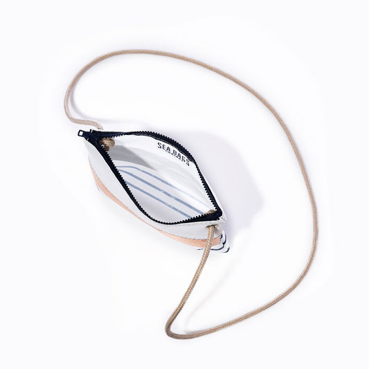A Rose Gold-on-Navy Mariner Stripe Slim Crossbody Bag by Sea Bags, featuring a small handcrafted design with a tan rope strap and zippered closure, is shown open to reveal a white interior with blue Breton stripes and the SEA BAGS logo printed inside, photographed on a plain white background. by Sea Bags
