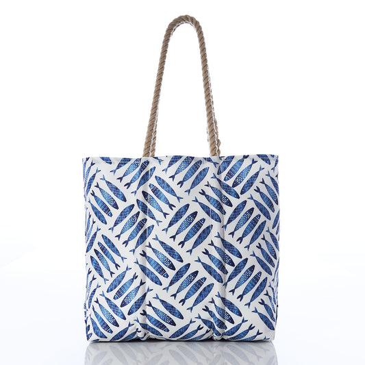 The Sea Bags Fish Print Medium Tote with Clasp, crafted from recycled sails and adorned with a blue fish pattern, features sturdy twisted rope handles. Displayed on a plain white background, this weather-resistant accessory is perfect for your next seaside adventure. by Sea Bags