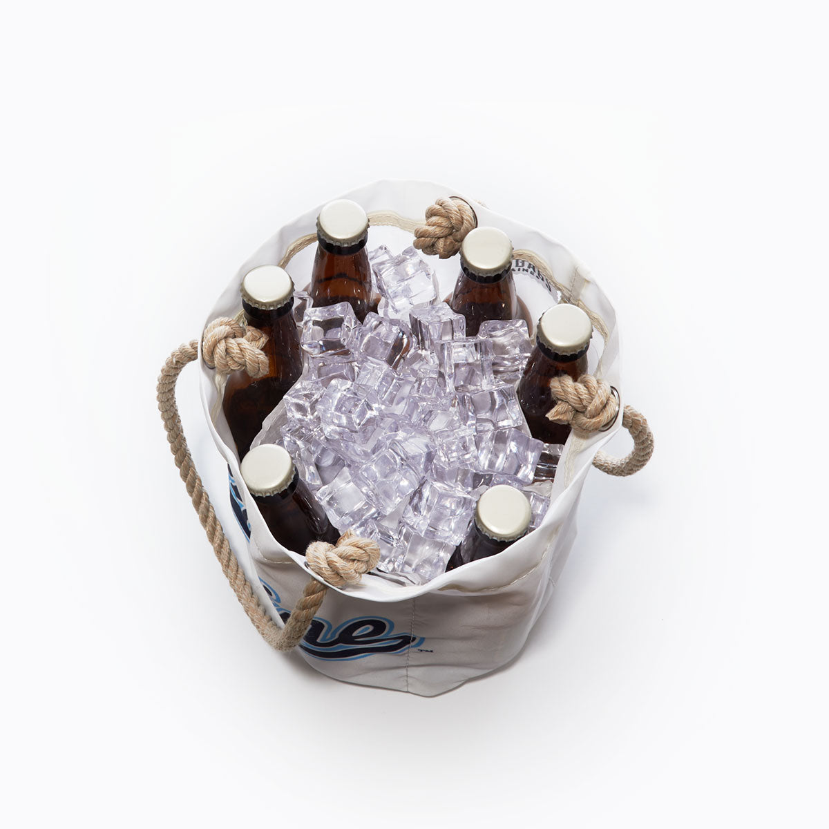 Six brown glass bottles in a white Sea Bags UMaine Beverage Bucket filled with ice cubes, shown from above. The bucket, crafted from recycled sail cloth, features thick rope handles and blue lettering on the side—evoking the classic style of a University of Maine bucket. by Sea Bags