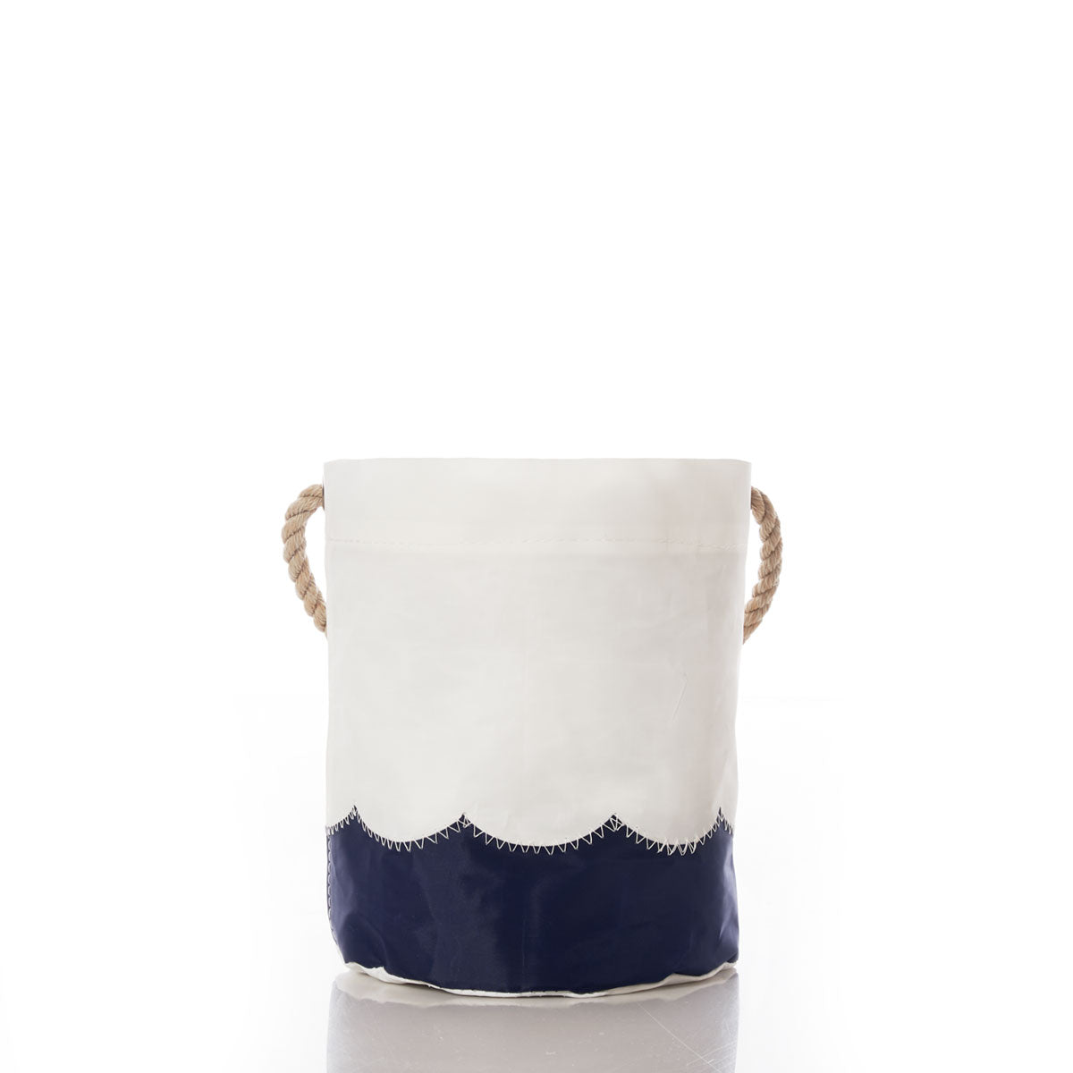 The Sea Bags Wavy Seas Bucket Bag features a small cylindrical shape with a navy blue scalloped bottom, an off-white upper section, and two thick rope handles on each side, offering effortless coastal charm and nautical style against a white background. by Sea Bags