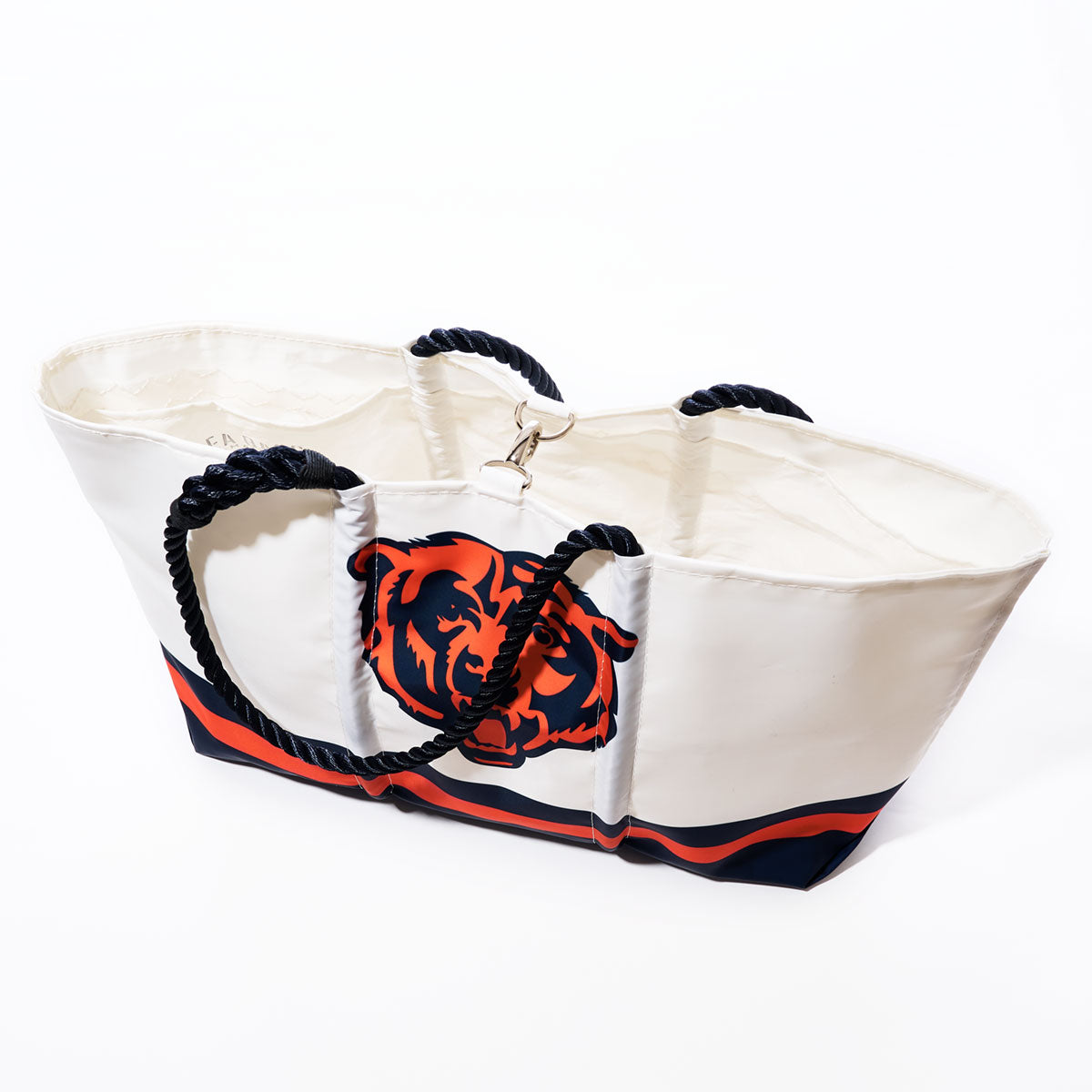 The Sea Bags Chicago Bears Tailgate Tote is a large white tote bag made from recycled sail cloth, featuring navy rope handles, navy and orange stripes, and the official Chicago Bears NFL logo. The tote is photographed on a white background. by Sea Bags