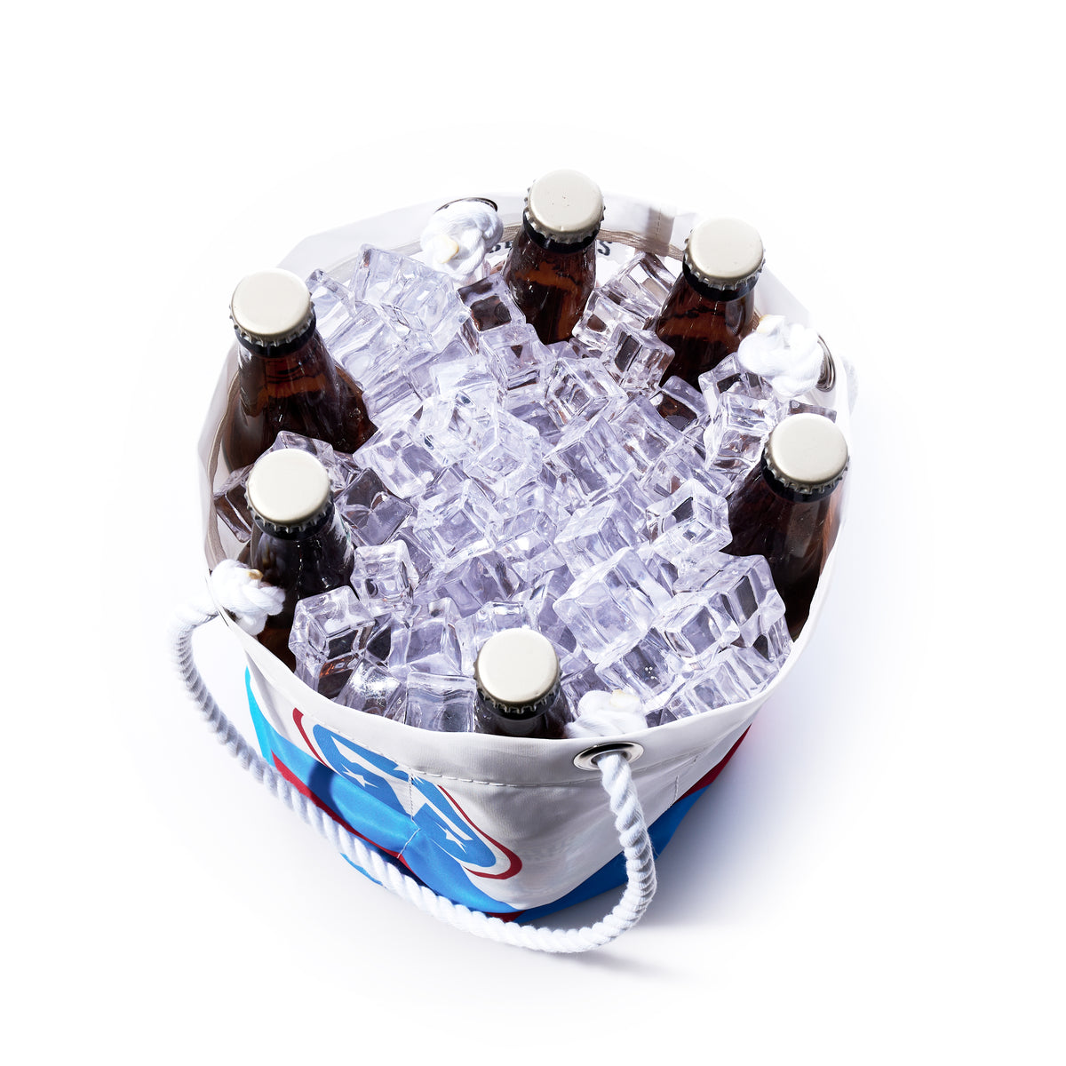 A top-down view of six capped glass bottles in the Tennessee Titans Beverage Bucket by Sea Bags, a white and blue sustainable cooler made from recycled sail cloth, filled with ice cubes. by Sea Bags