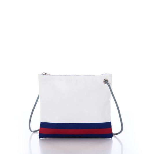 The Sea Bags New York Giants Slim Crossbody is a white crossbody bag made from recycled sail cloth, featuring a blue and red stripe along the bottom, a zipper closure, and a gray cord strap. Inspired by the iconic New York Giants bag style, it is displayed against a white background. by Sea Bags