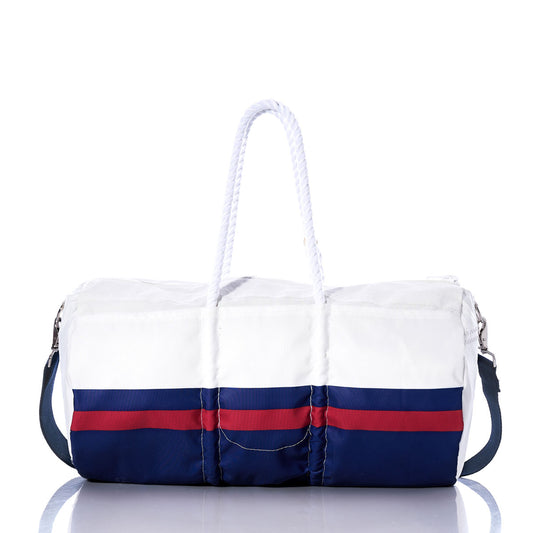 The New York Giants Duffel by Sea Bags, crafted from recycled sail cloth with blue and red stripes, features white rope handles and a detachable shoulder strap. It is displayed on a reflective surface. by Sea Bags