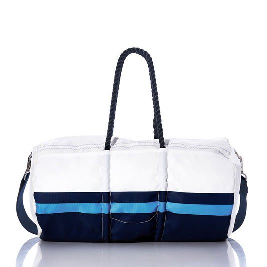 The Tennessee Titans Duffel by Sea Bags is crafted from recycled sail cloth in white and navy blue, featuring a light blue stripe, navy rope handles, and a shoulder strap. The bag is displayed on a reflective surface against a white background. by Sea Bags