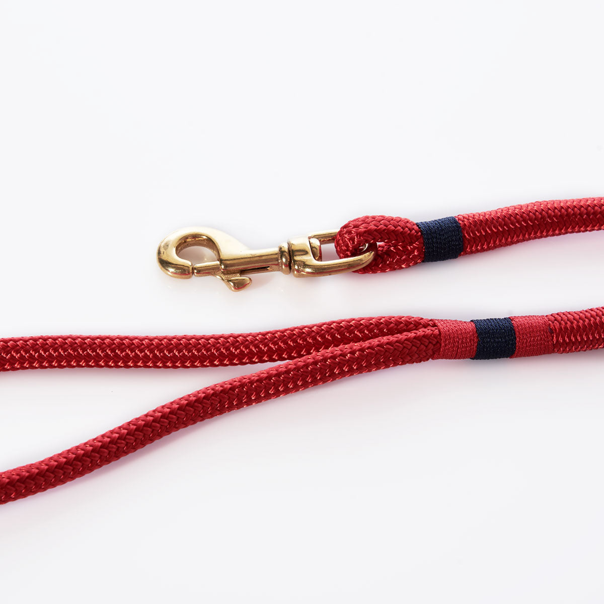 The Maine Rope Dog Leash - Deep Red by Custom Cordage / DBA Maine Rope Mats is a handmade leash crafted from red braided rope with black accents and finished with a brass swivel snap hook. Coiled on a white background, this classic nautical-style leash is perfect for adventurous pets who love the yacht braid look. by Sea Bags