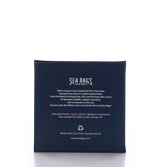 Galleyware’s Maine Landmarks Jigsaw Puzzle features a navy blue box with white text that highlights its Maine-themed map design, total piece count, recycled material usage, and manufacturing details. by Sea Bags