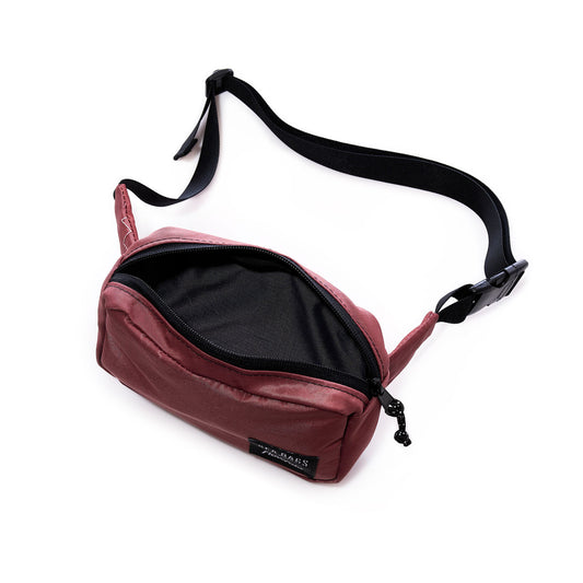 A Vintage Tanbark Crew Belt Bag by Sea Bags, shown unzipped with the main compartment open and empty, features a maroon recycled sail cloth body and a black adjustable strap with buckle—sustainably made from reclaimed materials. by Sea Bags