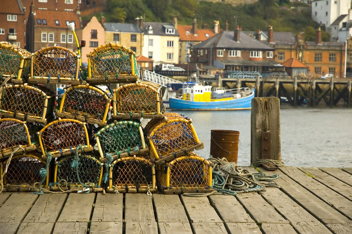 three recycled sail totes on a pier overlooking a waterfront town