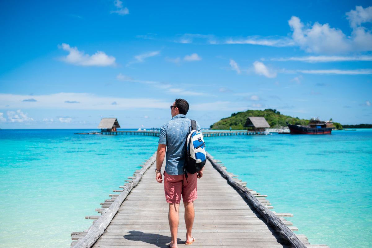 Backpack made from recycled sail, on man walking on pier near islands