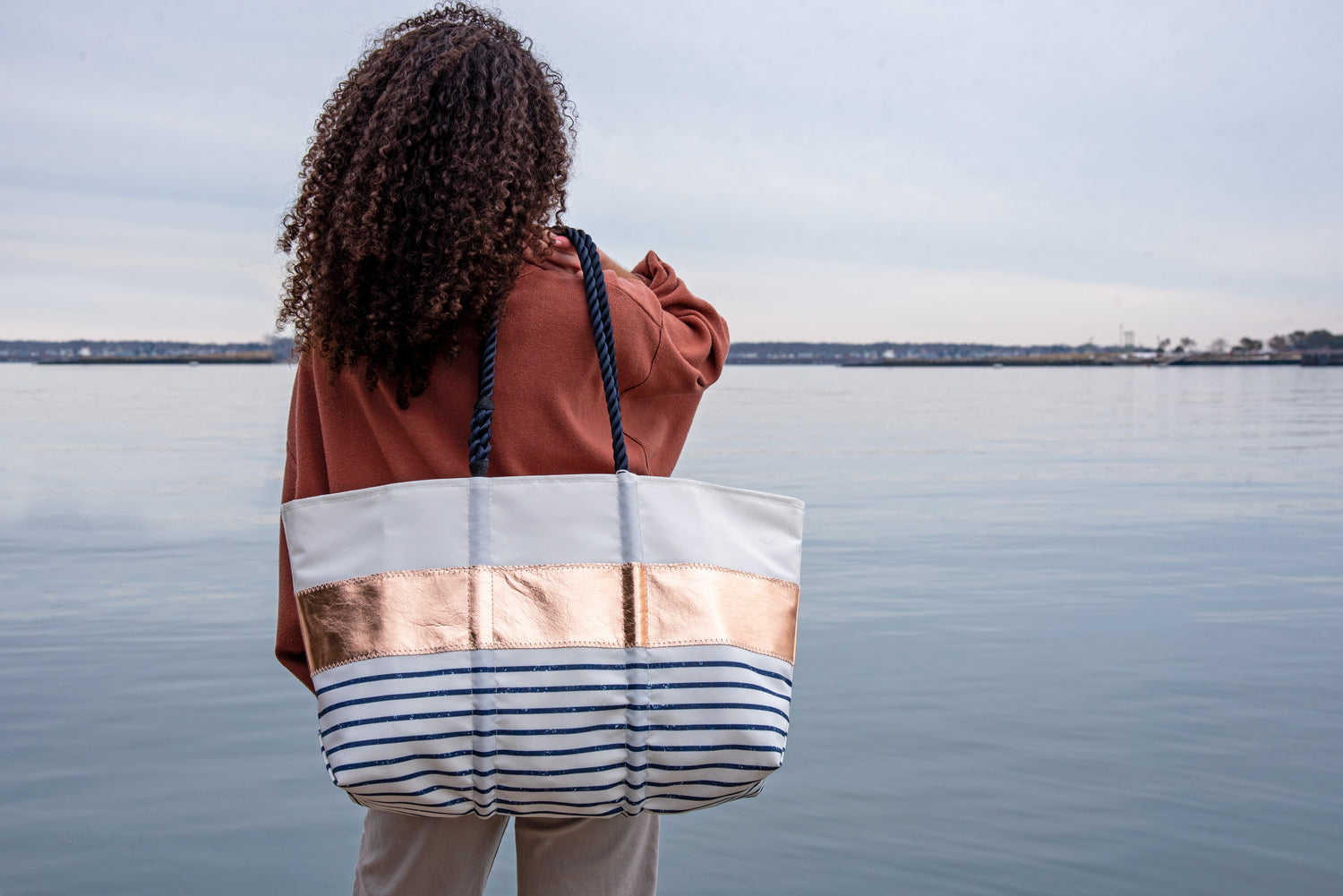Maine-made tote held by woman on the sea shore or harbor