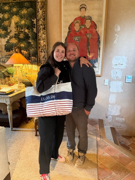 Two people standing together in a hotel on holiday, holding a custom date tote from Sea Bags